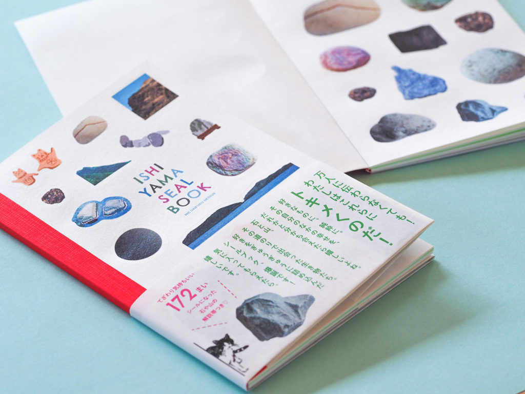 写真：石と山シールブックの表紙と中面。赤い背表紙に、帯つき。
