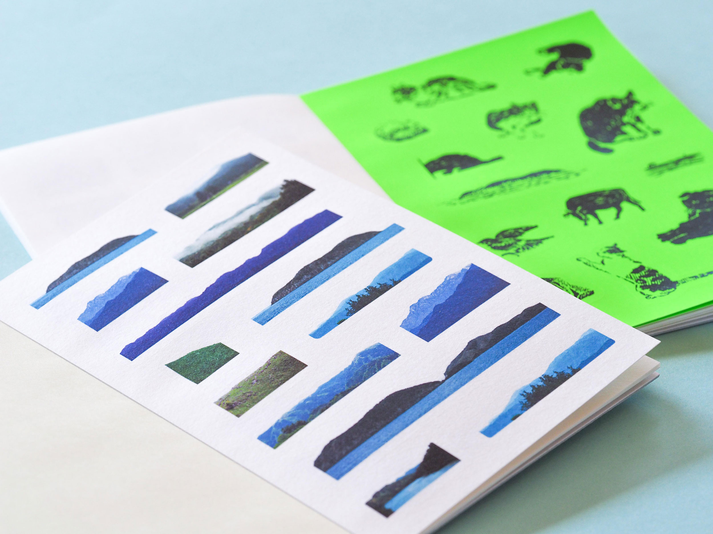 写真：自由な形のシールブックサンプル。風景のシールが並んだページと、蛍光グリーンの用紙に動物イラストが並んだページ