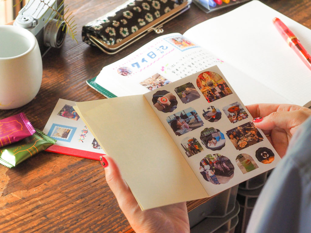 写真：手帳に向かってタイ旅行の写真がプリントされたシールブックを開いているところ