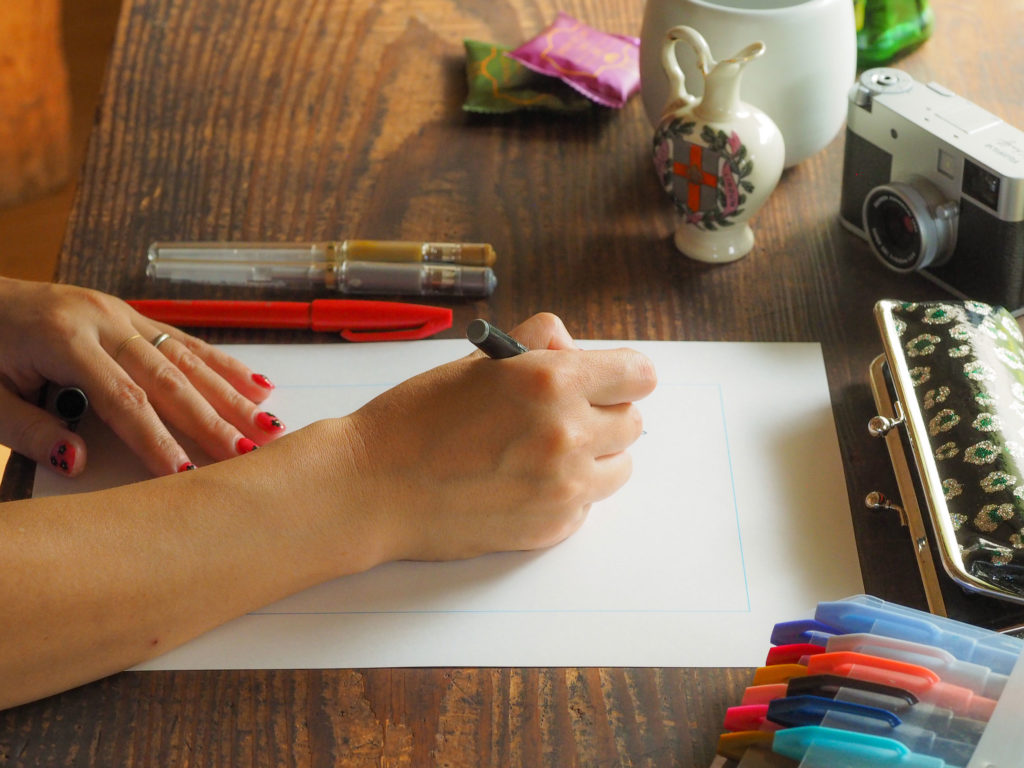 写真：真っ白なテンプレートにペンを走らせている手